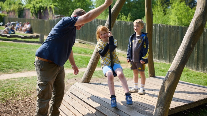 A child about to set off on a zip wire whilst another one waits behind her